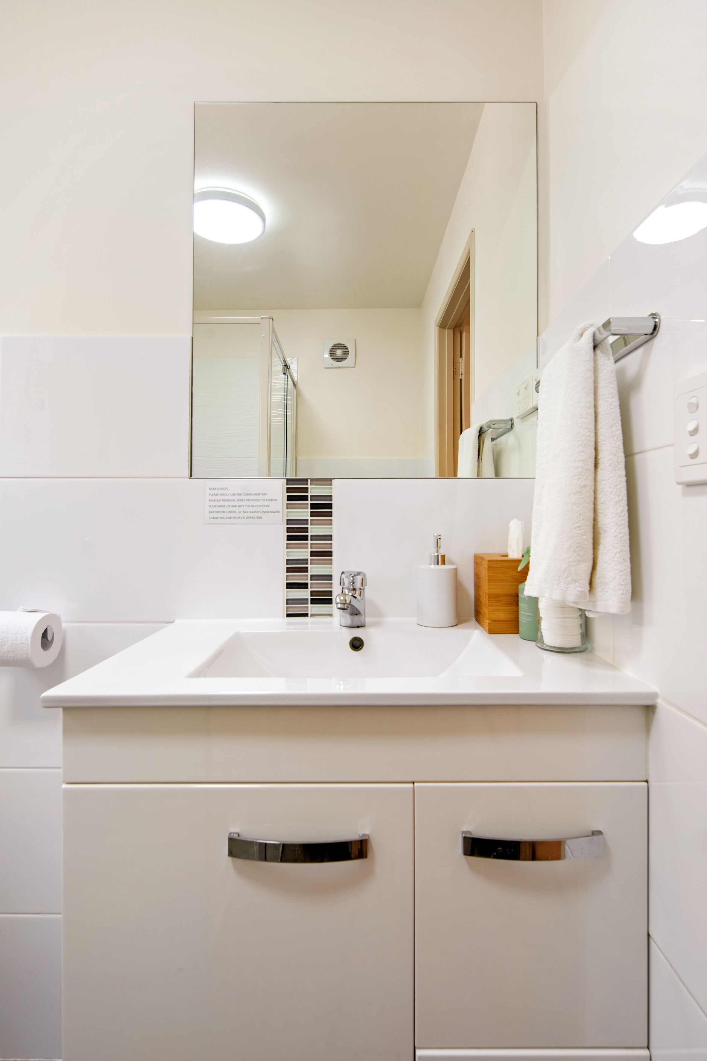 A bathroom with a white sink, mirror, and two drawers.