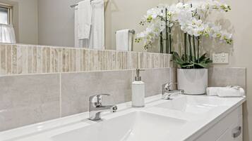 Un baño con un lavabo blanco, un espejo y una orquídea en maceta.