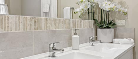 A bathroom with a white sink, a mirror, and a potted orchid plant.