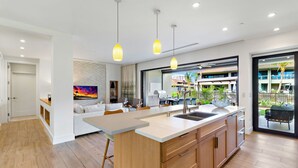 A modern kitchen with a central island, pendant lighting, and a view of a residential area.