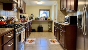 A kitchen with wooden cabinets, a stainless steel refrigerator, a microwave, a stove, and a sink. - Hunter Mountain Getaway House, newly renovated (Hunter)