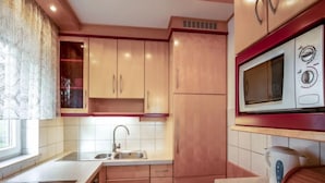 Une cuisine avec des meubles en bois, un évier en acier inoxydable et un four à micro-ondes encastré.