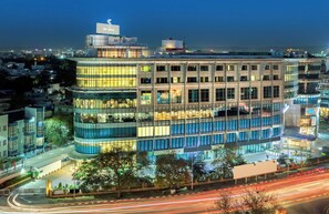 A multi-story building with a glass facade, a rooftop sign, and a parking area. - Sunday Hotel Jaipur (Jaipur)