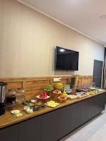 Un mostrador de buffet con diferentes alimentos y un televisor colgado en la pared.