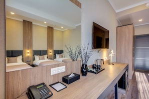 A modern hotel room with a wooden reception desk, a telephone, a tissue box, a vase with branches, and a flat-screen TV mounted on the wall. - Sara Hotel Bishkek (Bishkek)
