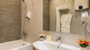 A modern bathroom with a bathtub, a vanity with a sink, and a large mirror.