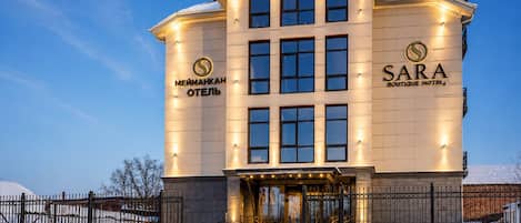 A multi-story hotel with a prominent entrance, large windows, and a well-lit facade.