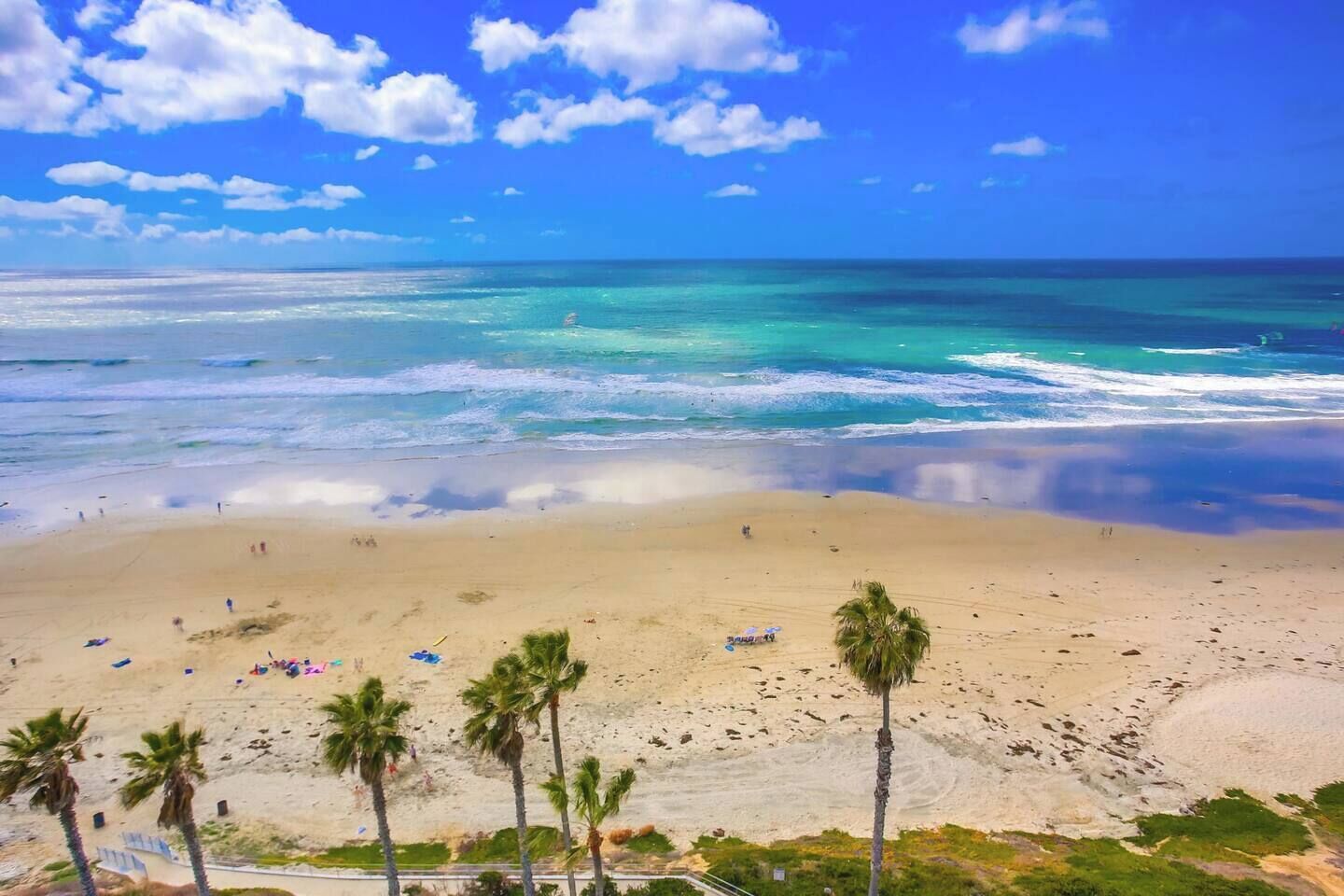 A beach with clear skies, calm sea, and palm trees.
