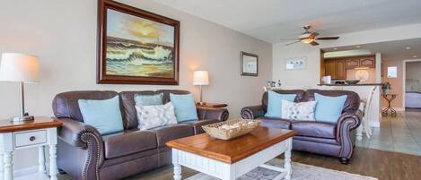 A living room with two leather sofas, a wooden coffee table, and a painting on the wall.