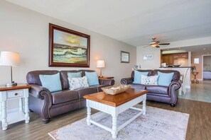 A living room with two leather sofas, a wooden coffee table, and a painting on the wall. - Panoramic 9th fl. Oceanfront view, parking, pool (San Diego)