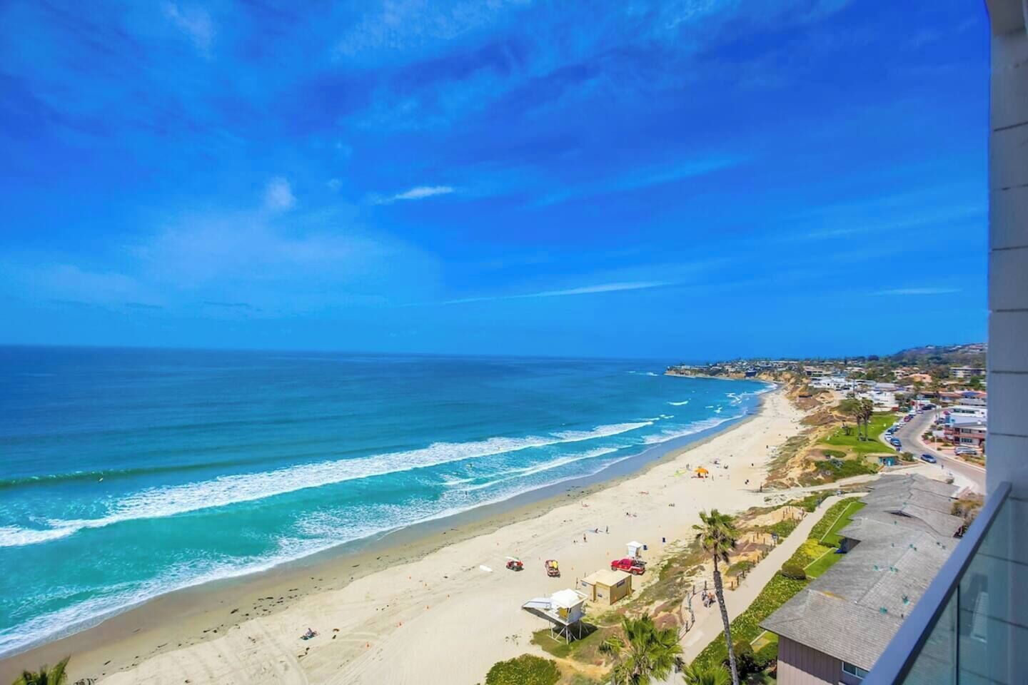 A coastal view with a beach, ocean, and buildings along the shore.