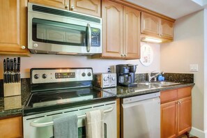 A kitchen with a microwave, stove, coffee maker, and dishwasher.