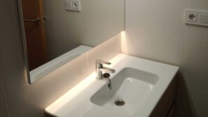 A bathroom with a white sink, a mirror, and a wooden cabinet.
