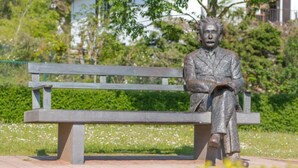 Une statue représentant un homme assis sur un banc dans un parc.