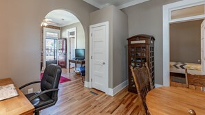 Un salon spacieux doté d’un parquet, d’une table à manger et d’un téléviseur placé au fond de la pièce.