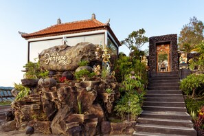 A villa named "Villa Jempano" with a stone facade, a red-tiled roof, and a staircase leading to a door with traditional decor. - Villa Jempana (Kintamani)
