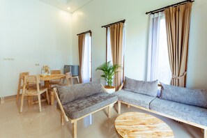 A modern living room with a wooden dining table, two sofas, and a coffee table.