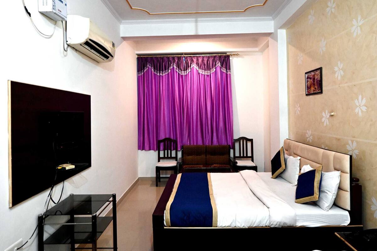 Une chambre d’hôtel équipée d’un lit, d’une télévision, d’un ventilateur de plafond et d’un bureau avec une chaise.