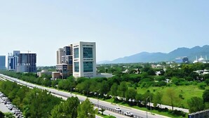 A modern cityscape with high-rise buildings, a highway, and a green park area. - Viridi Hotels (Islamabad)