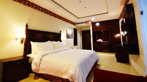 A hotel room with a large bed, a wardrobe, a television, and a bathroom visible through an open door. - Viridi Hotels (Islamabad)
