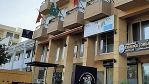 A multi-story hotel with balconies, flags, and various signs indicating amenities and services. - Viridi Hotels (Islamabad)