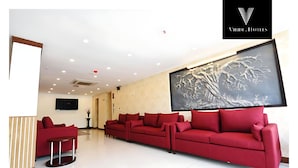 A modern hotel lobby with a red sofa set, a flat-screen TV, and a large abstract painting on the wall. - Viridi Hotels (Islamabad)