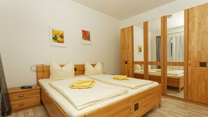 A bedroom with a wooden bed, a nightstand, a wardrobe, and two framed artworks on the wall. - Renovated vacation apartment Mare - Holiday apartment Mare in Zinnowitz (Zinnowitz)