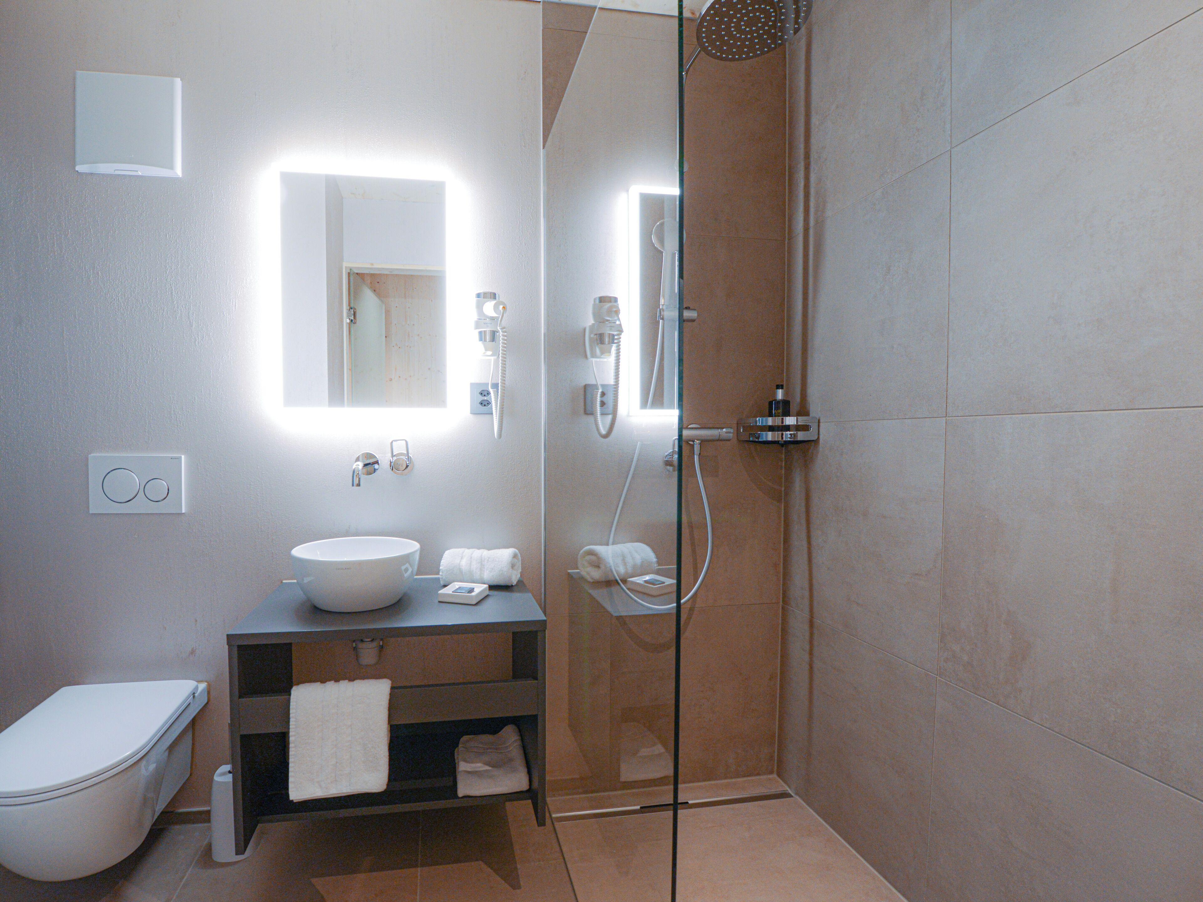 A modern bathroom with a glass-enclosed shower, a white sink, and a mirror.