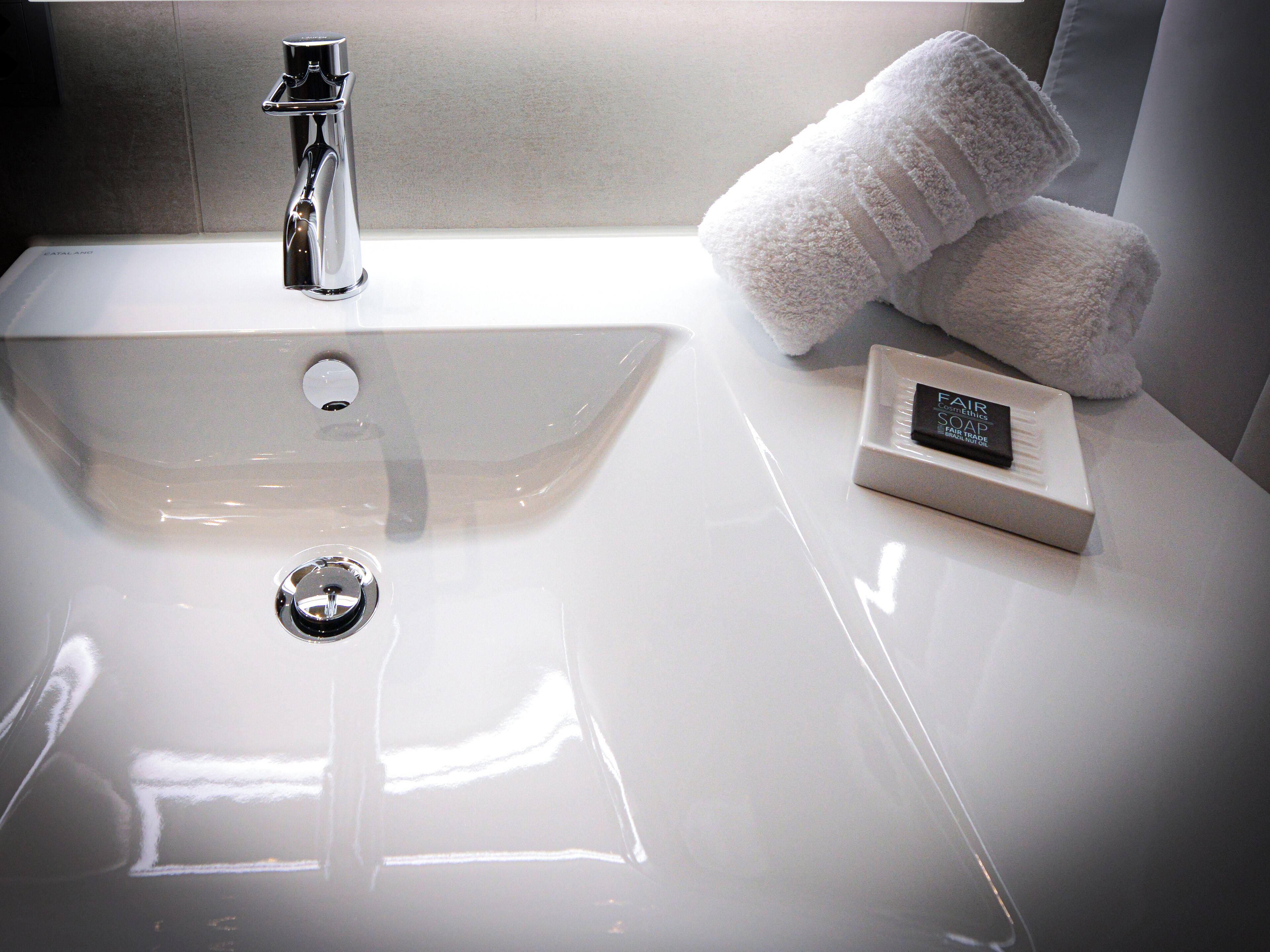 Un lavabo de salle de bain avec un robinet chromé, une serviette blanche et un distributeur de savon.
