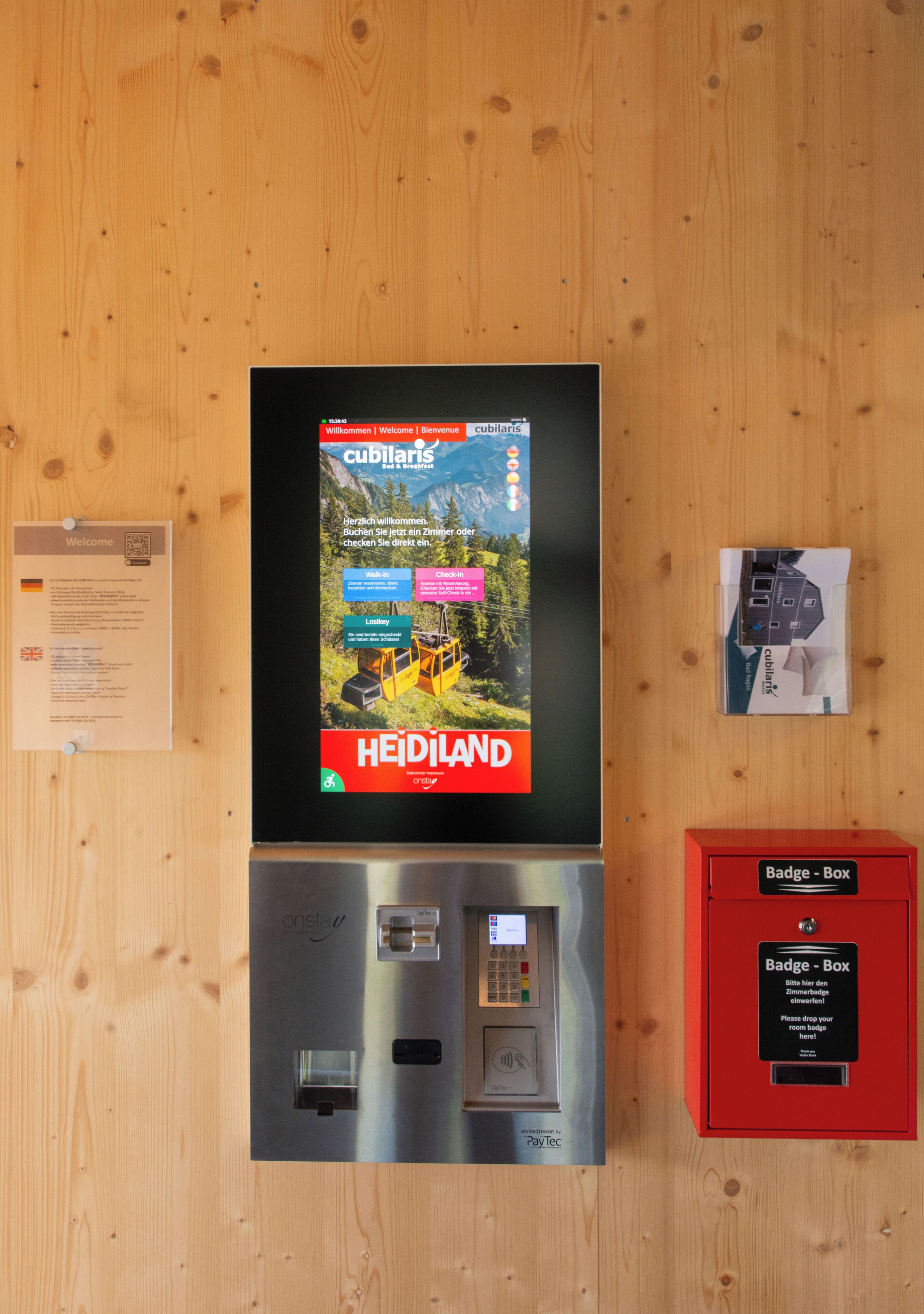 A digital display with a welcome message, a red badge box, and a payment terminal.