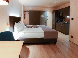 Una habitación de hotel moderna con una cama grande, un escritorio y una kitchenette.