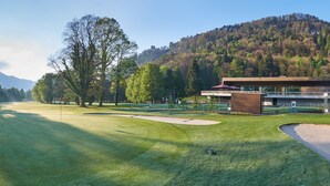 A golf course with a modern clubhouse, a mountain backdrop, and a clear sky. - Cubilaris Motel Bad Ragaz (Bad Ragaz)