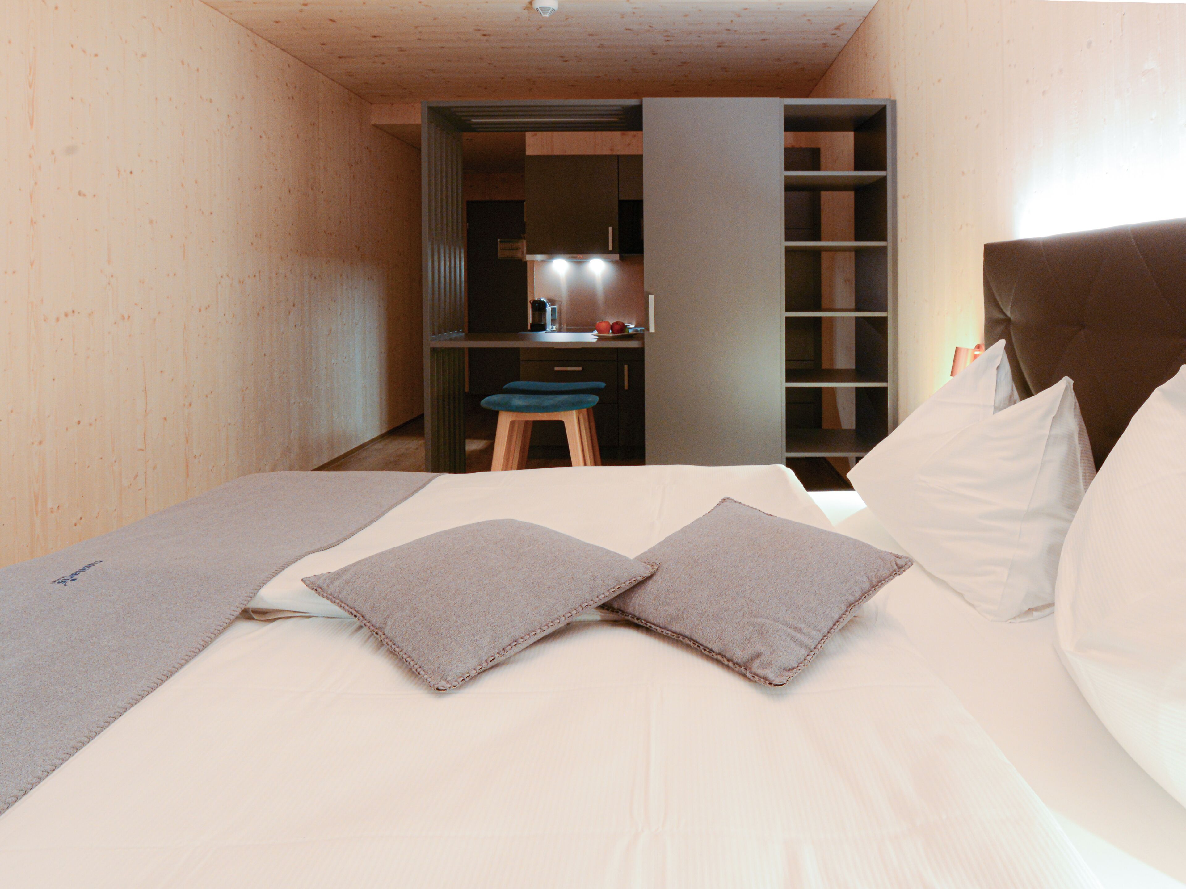 Un dormitorio con cama, almohadas, escritorio y una silla.