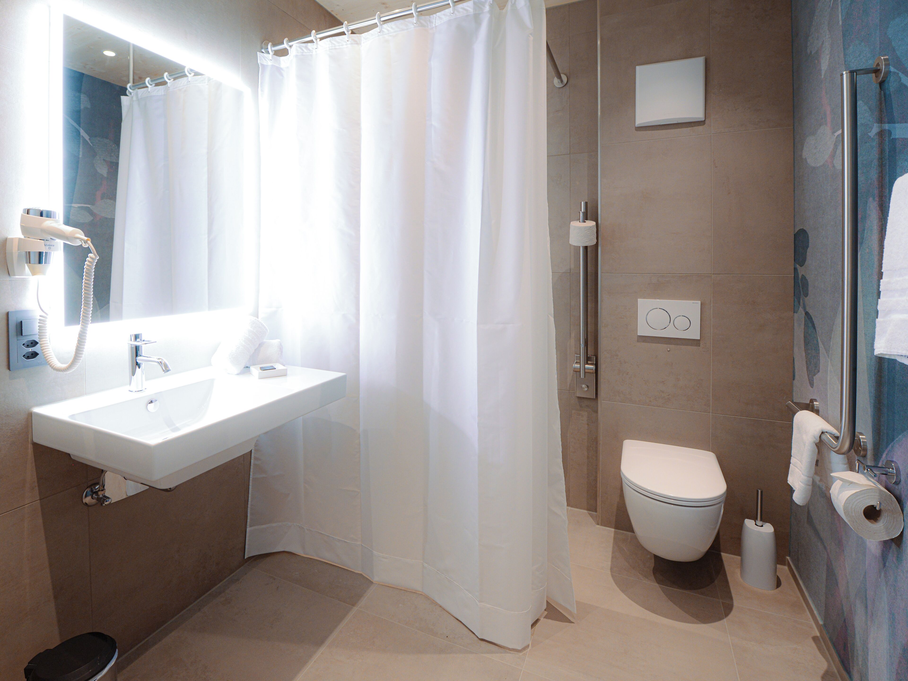 A modern bathroom with a white sink, a toilet, and a shower area.
