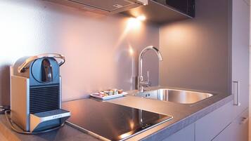 A modern kitchen with a built-in induction cooktop, a stainless steel sink, and a compact coffee machine.