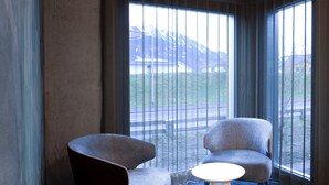A modern hotel room with a large window, two armchairs, a small round table, and a unique circular light fixture. - Cubilaris Motel Bad Ragaz (Bad Ragaz)