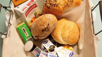 A basket containing a loaf of bread, a pastry, a box of milk, and several chocolate bars.