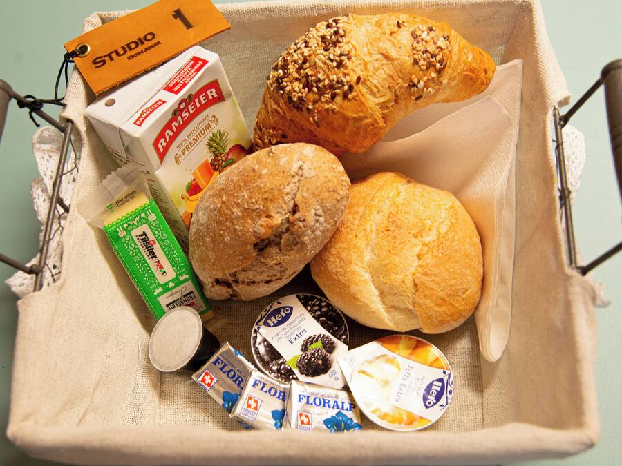A basket containing a loaf of bread, a pastry, a box of milk, and several chocolate bars.