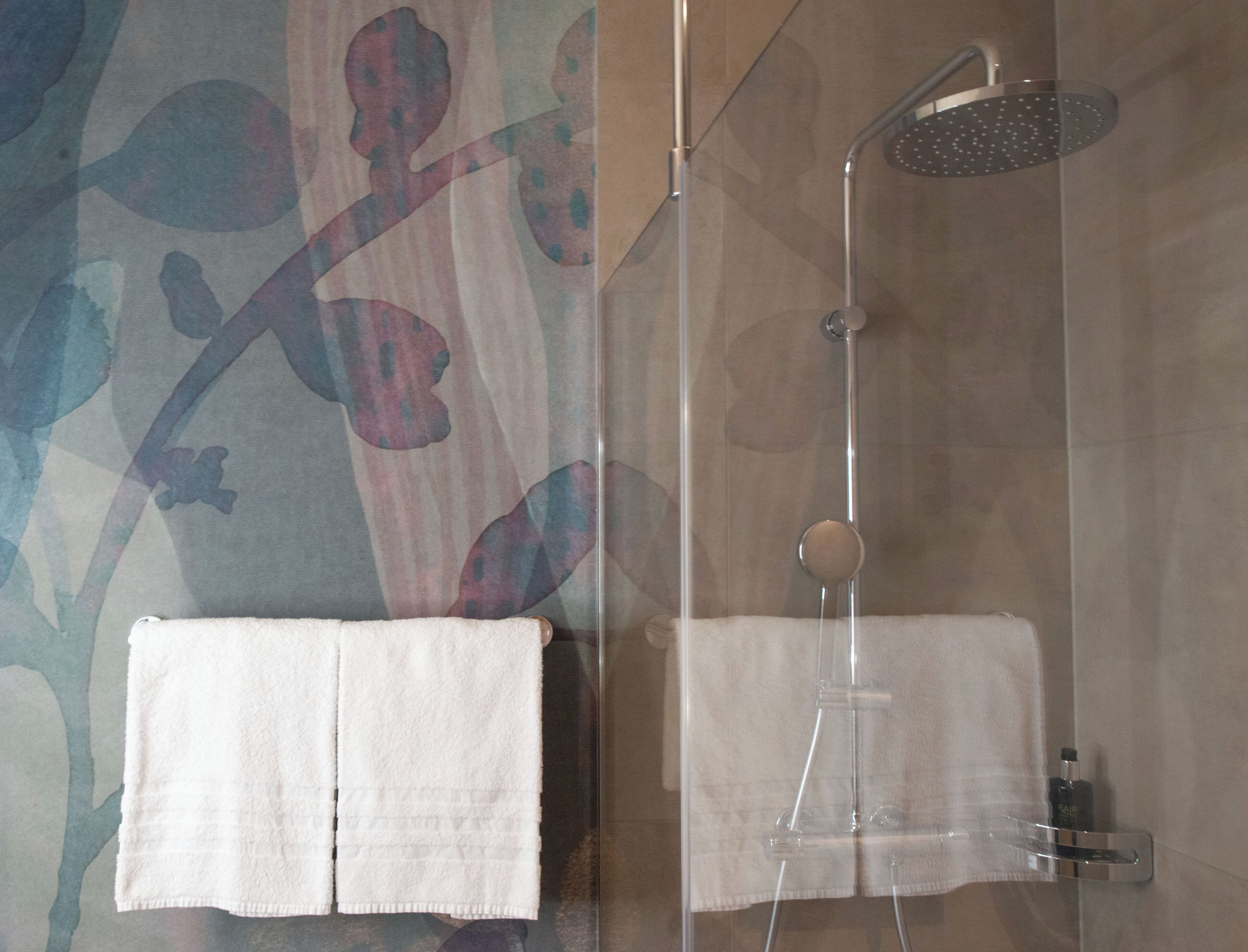 A bathroom with a shower, a towel rack, and a mirror.