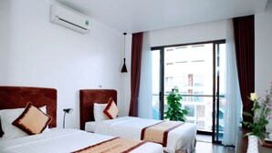 A hotel room with two beds, a large window with curtains, a potted plant, and an air conditioning unit on the wall. - Binh Minh Hotel (Dong Van)
