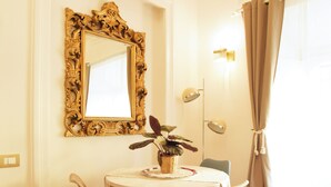 A dining area with a round table, two chairs, a mirror with an ornate frame, and a potted plant. - ♡♡♡ Norma ♡♡♡ (Roma)