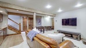 A modern living room with a leather sofa, a foosball table, and a flat-screen TV mounted on the wall. - Townhome ~ 4 Mi to Beaver Creek & 8 Mi to Vail! (Avon)