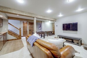 Ein modernes Wohnzimmer mit einer Ledersofa, einem Kicker und einem flachbildfernseher an der Wand.