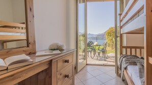 A bedroom with a wooden desk, a bed, and a balcony with a table and chairs. - Palma Romantic Dream (Perledo)