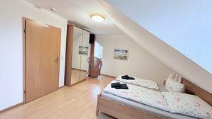 Un dormitorio con cama de madera, una silla, un armario y un espejo.