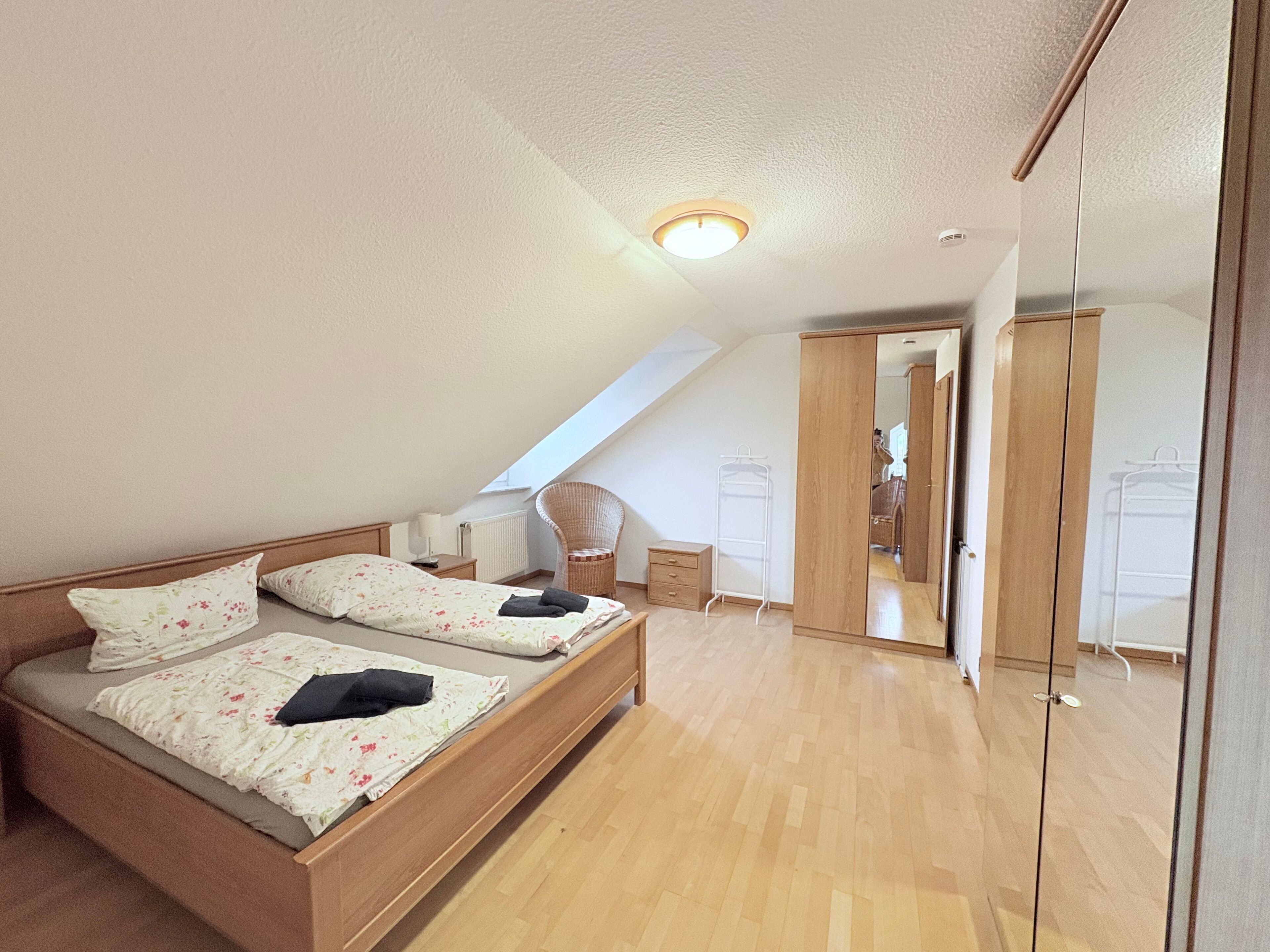 Un dormitorio con cama, una silla, un armario y un radiador.