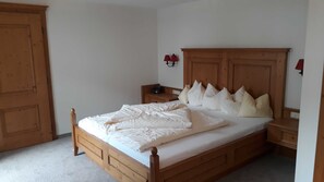 A bedroom with a wooden bed, nightstands, a dresser, and a wardrobe.