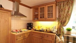 Une cuisine avec des meubles de rangement en bois, une cuisinière et une fenêtre avec des rideaux.