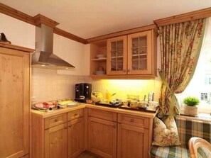 A kitchen with wooden cabinets, a stove, and a window with curtains.