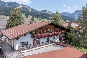 Ein Chalet mit einem geneigten Dach, einem Balkon mit Blumenkästen und Blick auf die Berge.